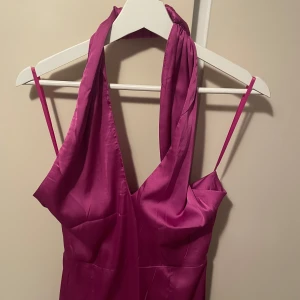 Lila/rosa Balklänning  - Snygg balklänning/långklänning i ett glansigt material. Klänningen har en slits framtill och en elegant passform som framhäver figuren. Det är en helt magisk färg som skiftar från lila till rosa i solskenet. Perfekt för bal eller liknande. Helt ny och har kvar prislappen, oanvänd. Skulle säga att den sitter som en s. Bara att höra av dig om du har frågor❤️pris går att diskutera
