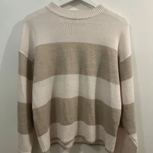Beige och vit randig tröja från H&M Divided - Säljer en snygg beige och vit randig tröja från H&M Divided. Tröjan är stickad med långa ärmar och har en bekväm passform. 