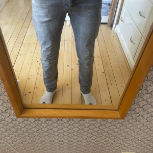 Grå jeansbyxor - Snygga grå jeansbyxor med en klassisk straight passform. De har en dragkedja och knappar framtill samt fem fickor. Perfekta för en avslappnad stil. Modellen är 180 och väger 68. Storleken på byxan är 29/30. 