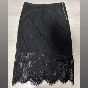 Svart spetskjol från Cubus - Supersnygg svart spetskjol i storlek 36. Kjolen har vacker spets nertill och en dragkedja i sidan. Perfekt för dig som gillar en elegant och stilren look med extra detalj i spetsen.