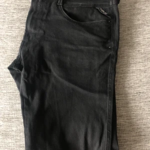 Svarta Replay Anbass jeans, stl 36/34 - Säljer ett par svarta Replay Anbass jeans i storlek 36/34. Jeansen har klassisk femficksdesign, normal passform och är tillverkade i mjukt jeansmaterial. Snygg och stilren look som funkar till många olika outfits. Jeansen är oanvända och modellen är 189cm lång och väger 70kg