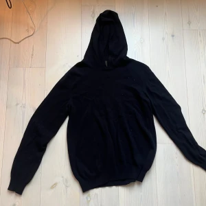 Mörk blå hoodie i kashmir från Oscar Jacobson - Mjuk och lyxig mörkblå hoodie från Oscar Jacobson i kashmir. Klassisk modell med huva och långa ärmar, perfekt för en stilren och avslappnad look. Tillverkad i Italien och passar dig som gillar premiumkänsla och enkel design.