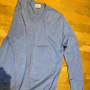 Ljusblå stickad tröja John Henric - Snygg ljusblå stickad tröja från John Henric med v-ringad hals och lång ärm. Perfekt för lager-på-lager och passar till både jeans och chinos. Mjuk och tunn kvalitet som känns skön mot huden.