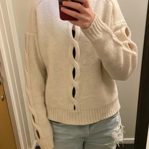 Vit stickad tröja från Filippa K - Säljer en vit stickad tröja från Filippa K med grov flätstickning längs ärmar och framtill. Tröjan har lång ärm, ribbade muddar och en relaxed passform. Perfekt för dig som gillar en stilren men ändå unik look . Pris kan diskuteras!