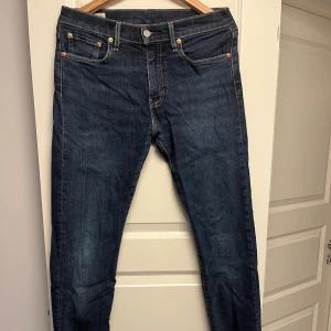 Levi's Premium 502 mörkblå jeans - Mörkblå Levi's Premium 502 jeans med klassisk femficksdesign och snygga kontrastsömmar. Jeansen har rak passform och är tillverkade i slitstarkt denim. Perfekta för dig som gillar en tidlös och clean look. Storlek: W30 L34      Nypris: 1049.
