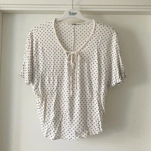 🍒Soft touch topp🍒 - 🍒SOFT TOUCH🍒Supersöt vit topp med svarta prickar och knyt framtill vid halsen. Blusen har korta, lite lösa ärmar och en avslappnad passform.  Kommer i ett mjukt material som Ginas soft touch kollektion. Passar även S🍒