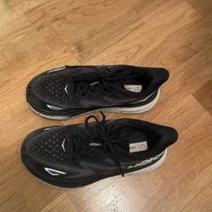 Svarta Hoka Clifton 9 sneakers -  Hoka Clifton 9. Använda fåtal  gånger, lite skadat på gummit som man kan se på bild 3, annars i superskick!