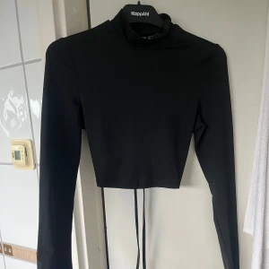 Svart croppad polotopp från SHEIN - Svart långärmad croppad polotopp från SHEIN med snörning i ryggen, aldrig använt 
