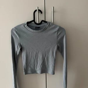 Ljusblå croppad långärmad topp Gina Tricot - Säljer en ljusblå croppad långärmad topp från Gina Tricot i storlek XXS. Toppen har rund halsringning och är tillverkad i mjuk bomull, perfekt för en clean och enkel look.