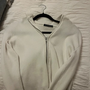 Vit ribbad kofta från Brandy Melville - Säljer en vit ribbad kofta från Brandy Melville med dragkedja framtill. Koftan har långärmad design och är tillverkad i mjukt material som passar perfekt till lager-på-lager. Enkel och stilren look som funkar året runt. Lite kortare. Stl xs-S