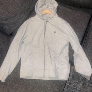 Grå hoodie från Polo Ralph Lauren - Snygg ljusgrå hoodie från Polo Ralph Lauren i storlek M. Änvänd 3 gånger och är som ny. Hör av er ifall ni vill köpa eller byta!