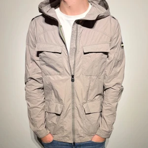 Colmar Field Jacket Windbreaker - Sjukt snygg field jacket med luva / windbreaker från colmar i väldigt fint skick! Storlek 50, sitter som M ungefär, kan även passa L. Hör av er vid frågor!