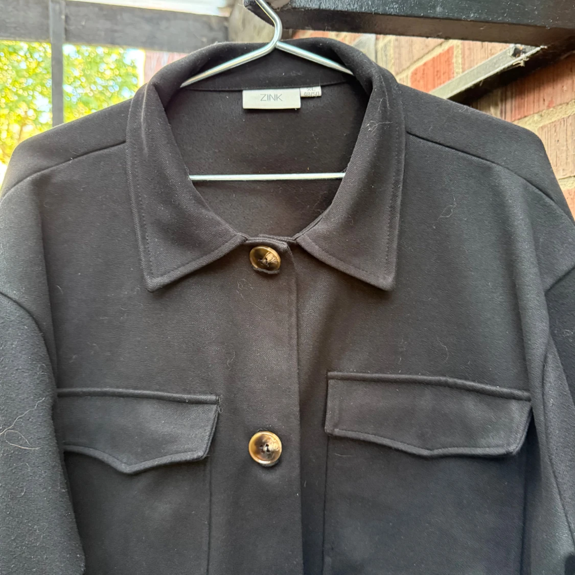 Höstjackan, svart, med två bröstfickor.