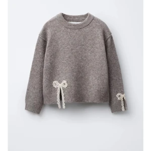 Beige stickad tröja med spetsrosetter - Superfin beige stickad tröja med söta spetsrosetter i vitt på ena ärmen och vid midjan. Perfekt för dig som gillar gulliga detaljer och vill ha en mysig men ändå stylish look. 💓💓använd få gånger!