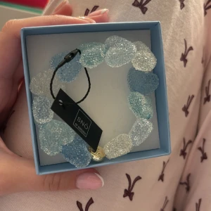 Blått och vitt armband från Snö of Sweden - Superfint armband från Snö of Sweden med frostade pärlor i blått och vitt. Pärlorna har en glittrig yta som ger ett isigt och unikt intryck. Kommer i original ask med randigt mönster. Perfekt accessoar för att lyfta din stil.