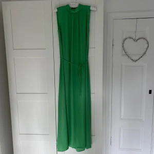 Grön långklänning från Saint Tropez - Säljer en snygg grön långklänning från Saint Tropez. Klänningen är ärmlös, har hög halsringning och ett smalt knytband i midjan. Så fin sommarklänning💕Endast använd en gång!