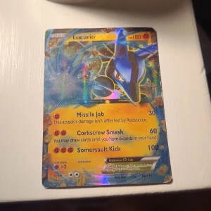 Lucario EX - Coolt och glittrande Lucario EX Pokémonkort! Perfekt för samlare och fans av Pokémon. Kortet har starka attacker som Missile Jab, Corkscrew Smash och Somersault Kick. Ett måste för dig som vill imponera på vännerna eller stärka din samling!