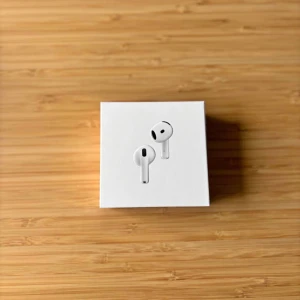 AirPods 4 - Nya Apple AirPods 4 med aktiv brusreducering, laddningsetui och USB-C kompatibilitet. Hörlurarna och förpackningen är i nyskick, inga synliga defekter eller slitage. Perfekt för musik, samtal och smidig anslutning till Apple-enheter.