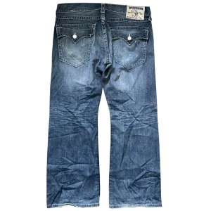 Blå jeans från True Religion - baggy true religion jeans. galen wash o passform. midja rakt över: 48cm. ytterben: 100cm. benöppning: 26cm. kom privat vid frågor
