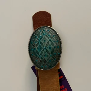 Brunt skärp från GAP med turkos spänne - Snyggt brunt bälte från GAP i äkta skinn med ett stort ovalt spänne i turkos och silver. Spännet har ett detaljerat geometriskt mönster och små blå stenar. Passar dig som har strl 25 i midjan.