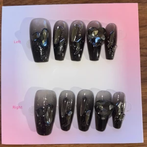 S - Svarta lösnaglar med stenar - Snygga lösnaglar i svart med glittrig finish. Naglarna har 3D-effekt med transparenta dekorationer och stora svarta hjärtformade stenar på ringfingrarna. Perfekt för dig som vill ha en edgy och glam look.