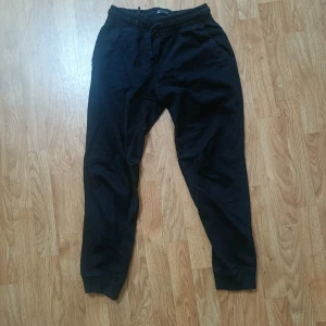 Svarta mjukisbyxor med resår - Svarta mjukisbyxor med resår i midjan och muddar vid bensluten. Byxorna har snörning i midjan och sidofickor samt en bakficka. Perfekta för chill eller träning, i mjukt bomullsmaterial.