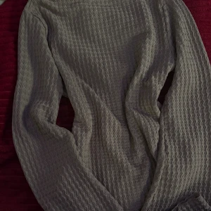  långärmad tröja med vågigt mönster Lager175 - Säljer en långärmad tröja med ett unikt vågigt mönster i tyget. Tröjan har en enkel och stilren design med rund halsringning och är perfekt för dig som gillar en clean look med lite extra struktur.