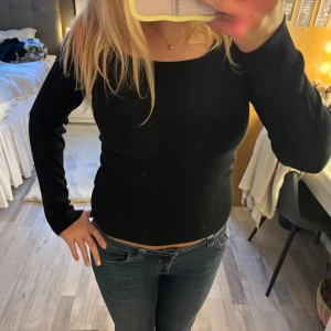 Svart ribbad tröja från Samsa Collection - Svart långärmad tröja från Samsa Collection med ribbad struktur och fyrkantig ringning. 