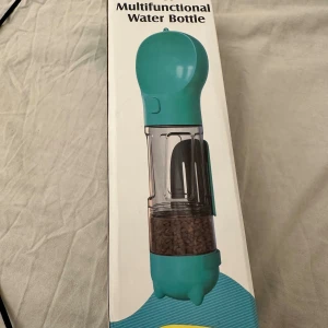 Pet Multifunctional Water Bottle multifunktionell vatten flaska  - Praktisk multifunktionell vattenflaska för husdjur med 300ml kapacitet, integrerad matskål och förvaring för bajspåsar. Ergonomisk design, enkel att använda med en hand och lätt att rengöra. Perfekt för promenader och resor. Produkten är ny i förpackning.