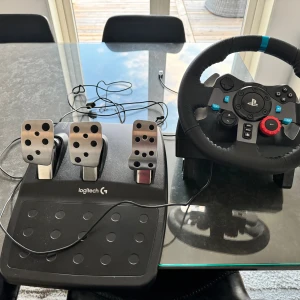 Logitech G29 ratt och pedalset - Logitech G29 ratt och pedalset för PlayStation och PC. Ratten har PlayStation-knappar, läderklädd yta och robusta metallpedaler. Allt ser välvårdat ut med minimalt slitage, perfekt för realistisk racingupplevelse hemma.