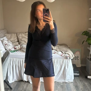 Mörkblå långärmad topp med spets(kan gå ner i pris)  - Säljer en mörkblå långärmad topp med v-ringning och fina spetsdetaljer vid halsringningen och ärmsluten. Toppens material är mjukt och stretchigt, vilket gör den bekväm och smickrande. Perfekt att styla med kjol eller jeans för en snygg look.