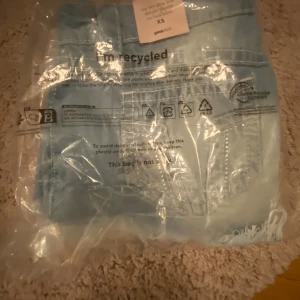 Ljusblå jeansshorts från Gina Tricot - Säljer ett par ljusblå jeansshorts från Gina Tricot i storlek XS. De har fransiga kanter, slitna detaljer och klassisk femficksdesign. Shortsen är lowwaist och har knapp och dragkedja framtill. Perfekta för varma dagar och en chill stil. Helt oanvända, beställde fel storlek och glömde att lämna tillbaka.