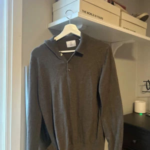 Brun polotröja från Bläck i ullmix - Snygg brun polotröja från Bläck med klassisk krage och knappar vid halsen. Tröjan är långärmad och tillverkad i en mjuk ullmix som passar perfekt till kyligare dagar. Enkel och stilren design som funkar till många outfits.