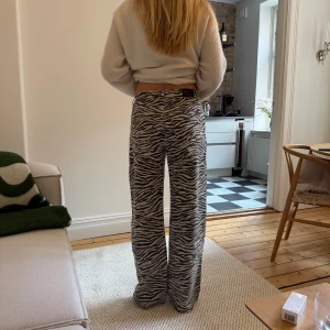 Zebramönstrade wide jeans - Säljer ett par riktigt snygga jeans med zebramönster i svart och beigt. Byxorna har en rak och wide passform med en lägre midja. Perfekta för dig som vill sticka ut och rocka en rolig outfit. Osäker på storlek, säg till om du vill veta exakt. Använda 2 gånger. 