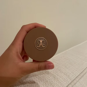Anastasia Beverly Hills Cream Bronzer - Krämig bronzer i färgen Golden Tan från Anastasia Beverly Hills. Kommer i en rund burk med brunt lock och guldig logga. Perfekt för att skapa en solkysst look med naturlig finish. Lätt att blenda och passar för contouring.
