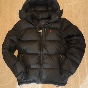 *Äkta* Polo Ralph Lauren Dunjacka  - Ralph Lauren jacka i använt skick! Har några lättare defekter så som ett mindre hål, och vanligt slitage. Den är fullt fungerande ett par vintrar till däremot. Självklart är den äkta. Mer information eller bilder fås i medellanden🤝