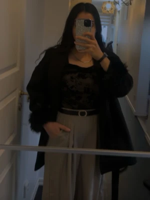 Svart meshblus med blommigt mönster - Säljer en svart meshblus med transparent tyg och sammetsliknande blommigt mönster. Blusen har lång ärm och en tight passform som framhäver siluetten. Perfekt att styla med både jeans och kjol för en trendig look.