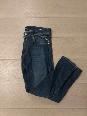 Replay Anbass jeans i mörkblå denim - Säljer ett par Replay Anbass jeans i mörkblå tvätt med klassisk femficksdesign och snygga kontrastsömmar. Perfekt för dig som gillar stilrena jeans med lite edge. Slim fit. 
