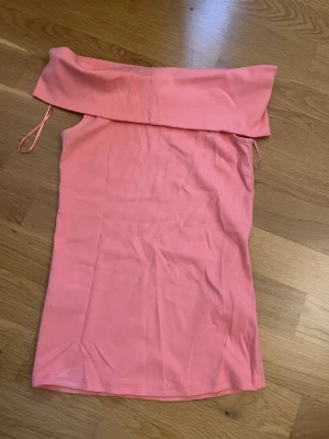Rosa ribbad offshoulder topp Gina Tricot - Säljer en ljusrosa ribbad offshoulder topp från Gina Tricot i storlek S. Toppen är axelbandslös med bred kant upptill och har en slim passform. Perfekt för sommarens alla tillfällen, enkel att styla med jeans eller kjol.