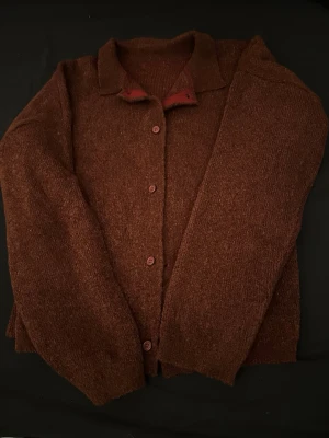 Vinröd stickad kofta med krage - Mysig vinröd stickad kofta med klassisk krage och knappar framtill. Koftan har långärmade och är tillverkad i ett grovstickat material som ger en skön och avslappnad känsla. Perfekt för lager-på-lager under kyliga dagar. Priset kan diskuteras 🤝