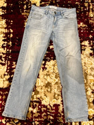 Ljusblå jeans från Smog/Denim - Säljer ett par ljusblå jeans från Smog/Denim med klassisk femficksdesign och snygga slitningar framtill. Jeansen har raka ben och normal passform, perfekta för en avslappnad stil. Tillverkade i mjukt denim-material.