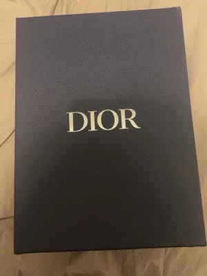Dior B30 svarta sneakers - Säljer ett par Dior B30 sneakers i svart med silvriga detaljer. Skorna har en modern och sportig design med mesh och syntetmaterial, samt snörning framtill. Ikonisk Dior-logga på plösen och sidan. Perfekta för dig som vill ha lyxiga och trendiga sneakers.