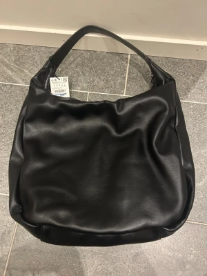 Handväska svart  - En svart handväska från pull&bear som är helt ny! Rymmer med ganska mycket, inklusive data. Vill gärna bli av med den och öppetköpet gick ut. Nypris 349kr