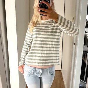 Randig långärmad tröja från H&M - Säljer en fräsch långärmad tröja från H&M i storlek XS. Tröjan har horisontella ränder i ljusgrått och vitt, rund hals och en normal passform. Perfekt för dig som gillar enkel och stilren design. Materialet är mjuk bomull som känns skönt mot huden. Oanvänd