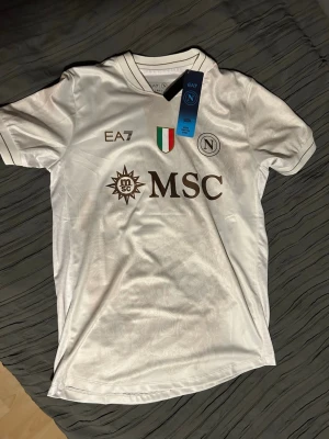 Napoli matchtröja - Säljer en helt ny Napoli matchtröja, årets bortaställ, med Lukaku och nummer 9 på ryggen. Tröjan är vit med snygga detaljer och de italienska mästarmärket på bröstet. Storlek S.