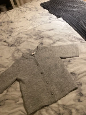 Grå stickad kofta från Gina Tricot - Mysig grå stickad kofta från Gina Tricot i storlek 146/152. Perfekt för lager-på-lager och chill dagar. Enkel och stilren design som funkar till många outfits. Använd en gång