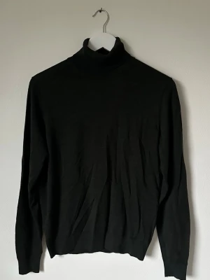 Mörkgrön polotröja från Uniqlo i ull - Säljer en mörkgrön polotröja från Uniqlo i storlek S, tillverkad i 100% ull. Tröjan har lång ärm och klassisk polokrage, perfekt för dig som gillar stilrena och tidlösa plagg. Passformen är normal och materialet är mjukt och skönt mot huden. 5L13