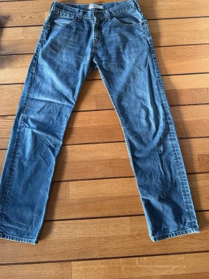 Levi's 504 blå jeans 32x32 - Klassiska blå Levi's 504 jeans med rak passform och normal midja. Tillverkade i 100% bomull för en autentisk jeanskänsla. Snygga detaljer med fem fickor och ikonisk röd Levi's-tag på bakfickan. Perfekta till sneakers eller boots.