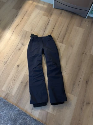 Mörkblå skidbyxor från J.Lindeberg XS - Snygga mörkblå skidbyxor från J.Lindeberg, modell W Watson Pant. Byxorna har dragkedjor vid fickorna och justerbar midja med kardborre. Perfekta för vintern och outdoor-aktiviteter. Materialet är slitstarkt och vattenavvisande. Helt nya! Nypris 4500, pris kan diskuteras vid snabb affär😊