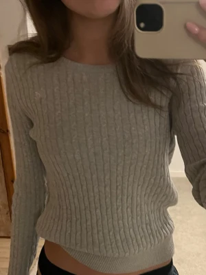 Tröja Gina  - En grå kabelstickad tröja med en rosa detalj ifrån Gina. Stl - M men passar S